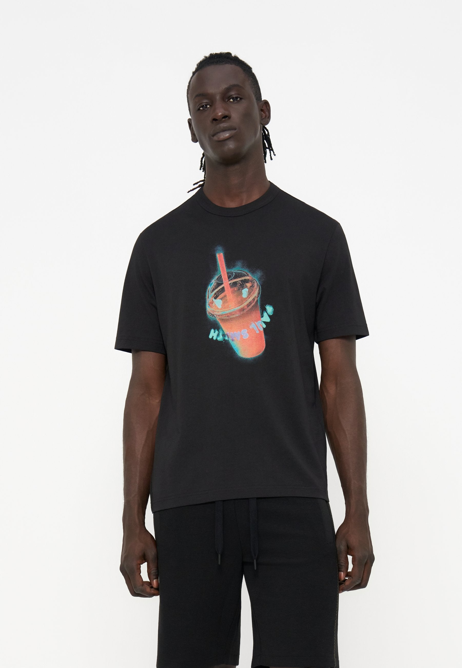 Junger Mann mit dunkler Haut und geflochtenem Haar, der ein schwarzes T-Shirt mit einer leuchtenden Smoothie-Becher-Grafik und dem Text „Happy Time“ trägt.