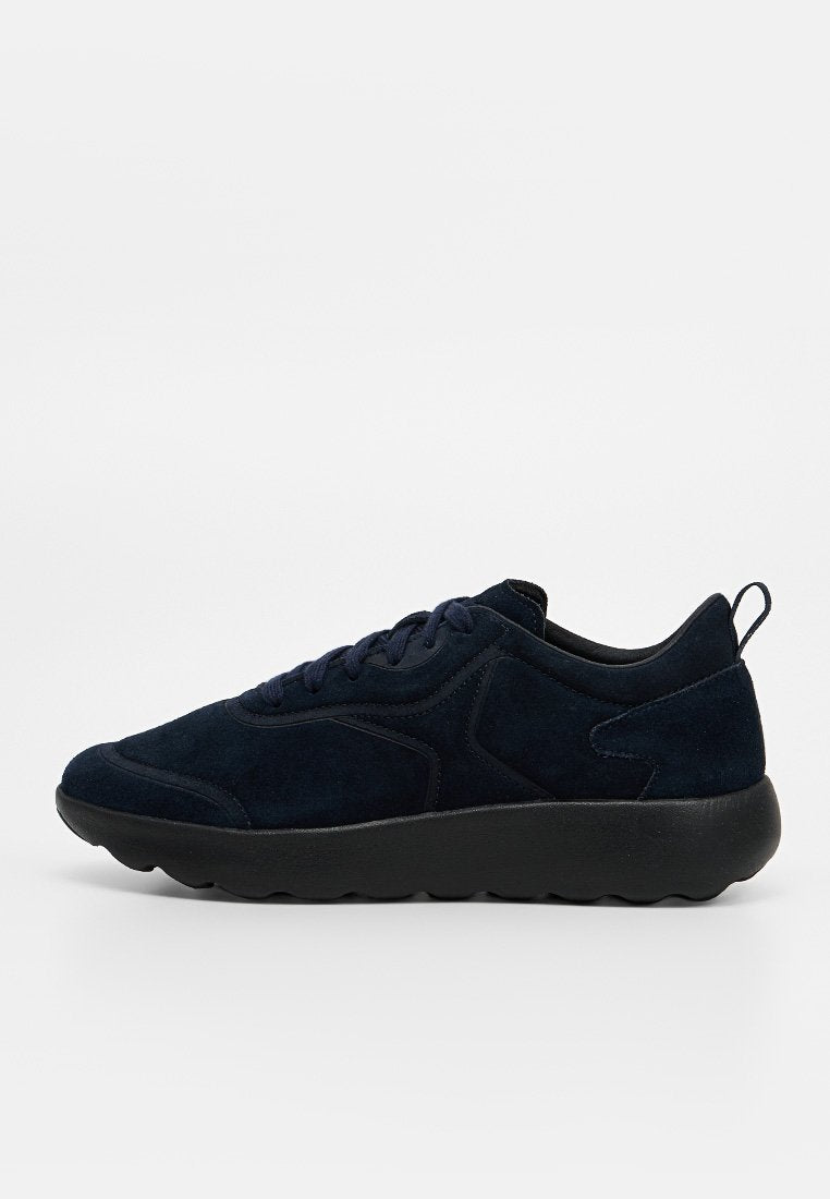 Dunkel marineblaue Wildleder-Sneaker mit schwarzer dicker Sohle, Schnürverschluss vorne und Zuglasche an der Ferse, seitlich auf weißem Hintergrund dargestellt.