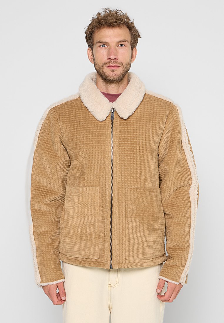 Beige Cord-Jacke mit einem cremefarbenen Lammfellkragen und -futter. Verfügt über zwei Fronttaschen und einen Reißverschluss. Strukturierter Stoff mit einem robusten Design.