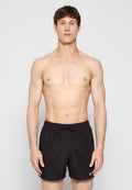 Schwarze Badeshorts mit Kordelzug am Bund, versehen mit einem kleinen weißen Nike-Logo auf der linken Seite. Glatte Textur, Standardpassform.