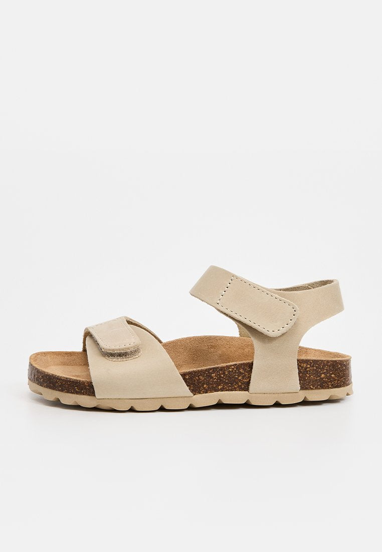 Beige Sandale mit offenem Zehenbereich, zwei verstellbaren Klettverschlüssen und einer korkstrukturierten Innensohle auf einer strukturierten beigefarbenen Sohle, Seitenansicht.