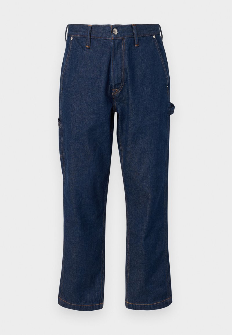 Dunkelblaue Jeanshose mit geradem Schnitt, mit kontrastierendem orangefarbenen Nähten und seitlichen Taschen, die mit einem Metallknopf verschlossen sind.