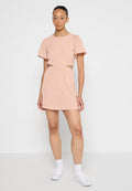 Rosa kurzes Kleid mit kurzen Puffärmeln, Cut-out-Details an der Taille und einem lockeren Schnitt. Getragen mit weißen Sneakers und Socken.