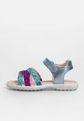 Glitzernde Sandale in Blau, Lila und Türkis, mit einem glänzenden silbernen Riemen. Strukturiertes Fußbett, gepolstertes Innere, verstellbarer Klettverschluss.
