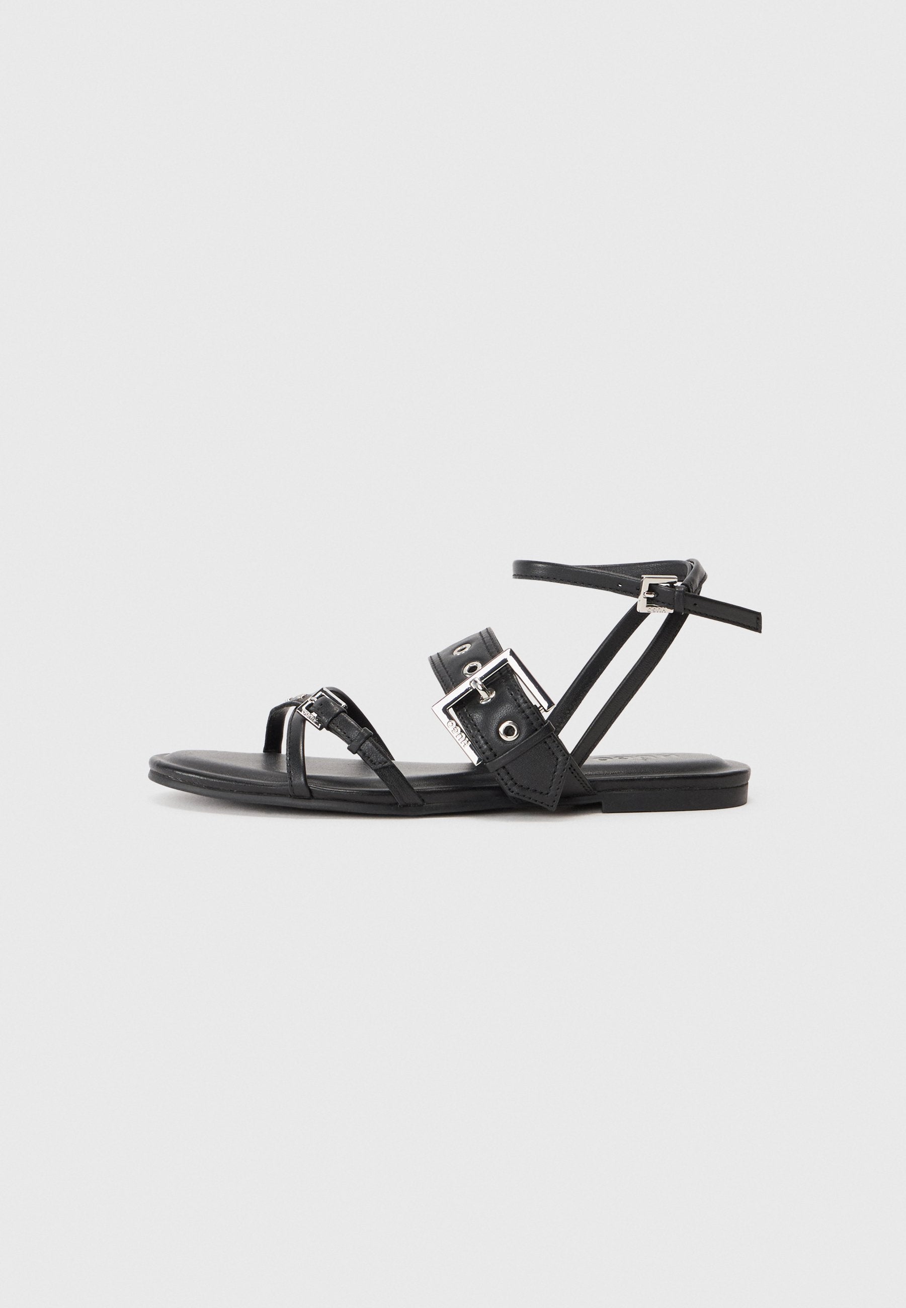 Schwarze Lederflache Sandalen mit mehreren Riemen, einer runden Zehenpartie und einer rechteckigen metallischen Schnalle. Minimalistisches Design mit einer eleganten Silhouette.