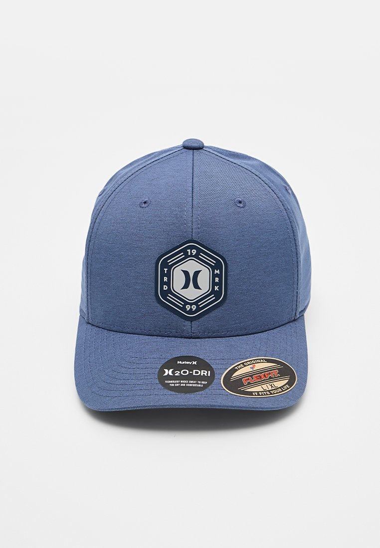 Blaues Baseballcap mit einem sechseckigen Logo, auf dem "19 TRD MRK 99" steht. Hergestellt aus atmungsaktivem Stoff mit strukturierter Form und flachem Schirm.