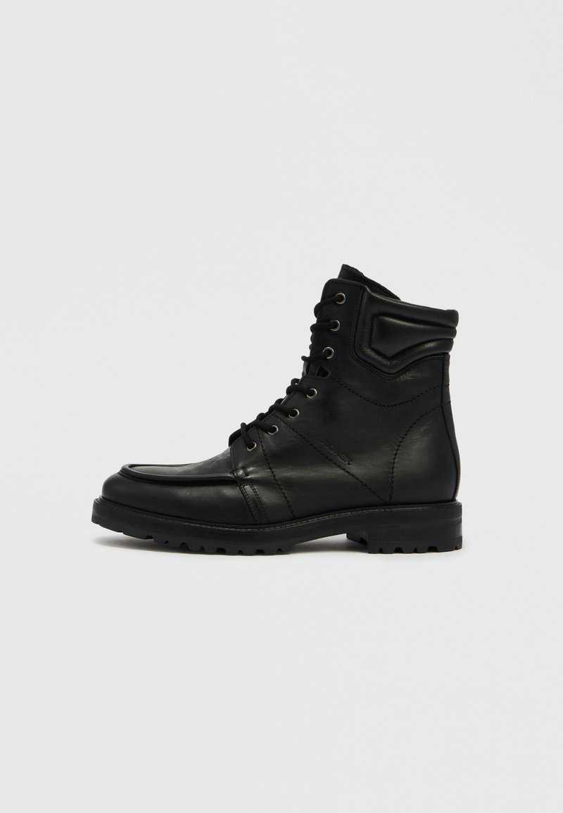 Schwarzer Leder-Stiefelette mit Schnürverschluss vorne, gepolstertem Kragen und robustem Profil, seitlich auf neutralem Hintergrund dargestellt.