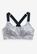Gemusterter Bralette in Weiß mit blauen und lila Punkten. Verfügt über überkreuzte marineblaue Träger und eine weiche Textur für zusätzlichen Komfort.
