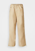 Beige, leichte Hose mit Kordelzugbund, seitlichen Reißverschlüssen und elastischen Bündchen. Glatte Textur, gerades Bein Design.
