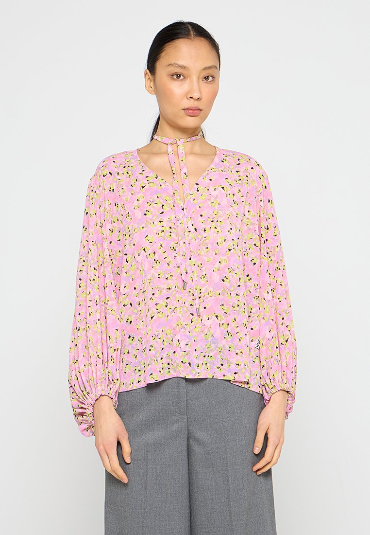 Bluse mit floralem Muster in Pink mit gelben und grünen Akzenten. Lockere Passform, lange Ärmel mit elastischen Bündchen und einer Bindegarnitur am Ausschnitt.