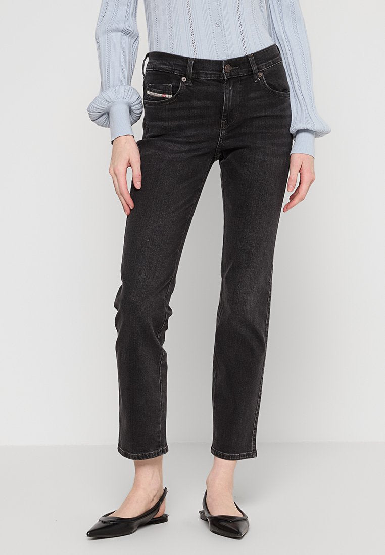 Schwarze Denim-Jeans mit geradem Bein, Knopfverschluss und fünf Taschen. Kombiniert mit einem hellblauen, gerippten Oberteil und schwarzen flachen Schuhen.
