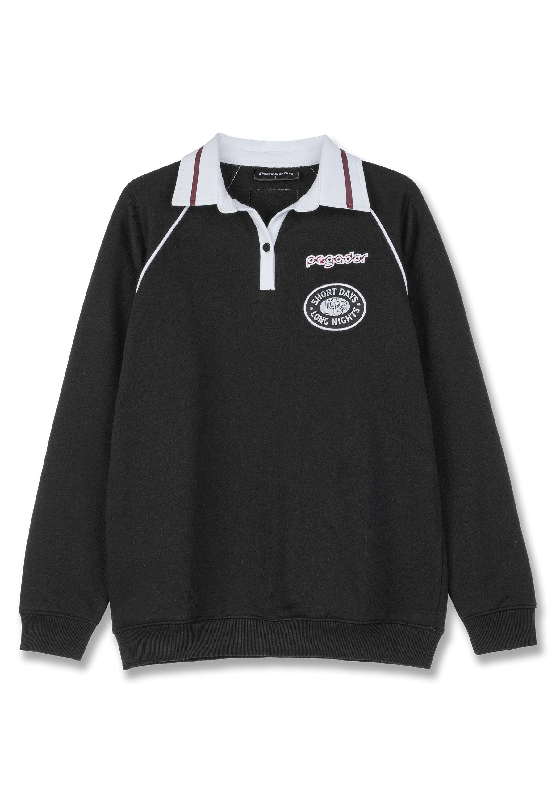 Schwarzer Langarm-Polo-Pullover mit weißem Kragen und roten Streifenakzenten. Mit gesticktem Logo und dem Text „KURZE TAGE LANGE NÄCHTE“. 