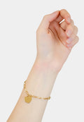Goldkettchen-Armband mit einem herzförmigen Anhänger, bestehend aus ineinandergreifenden Gliedern mit polierter Oberfläche, getragen an einer Hand.