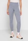 Frau trägt hochtaillierte graue Leggings mit melierter Textur, weiße Socken und beige Sportschuhe mit pinken Akzenten, steht vor neutralem Hintergrund.