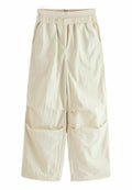 Beige, weit geschnittene Hose mit einem elastischen Bund, die zwei seitliche Taschen und eine strukturierte, zerknitterte Stoffoptik aufweist.