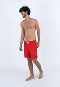 Rote Badeshorts aus leichtem Stoff, mit einem weißen Kordelzug, Seitentaschen und einem kleinen Markenlogo am Saum.