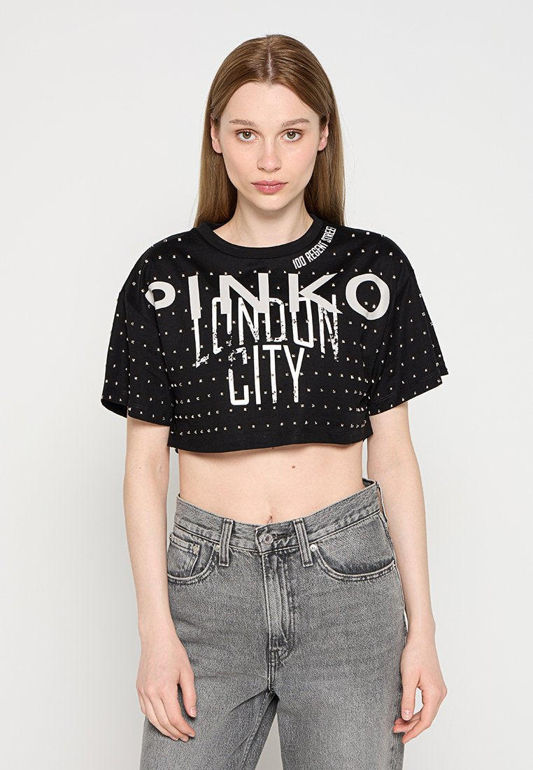 Schwarzes, kurzes T-Shirt mit weißem Drucktext "PINKO LONDON CITY", das ein Nietenmuster und einen runden Ausschnitt aufweist. Kombiniert mit grauen Jeans.