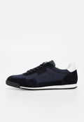 Low-Profile schwarzer und marineblauer Sneaker mit weißem Fersenakzent, schwarzen Schnürsenkeln und strukturierter Sohle auf weißem Hintergrund.