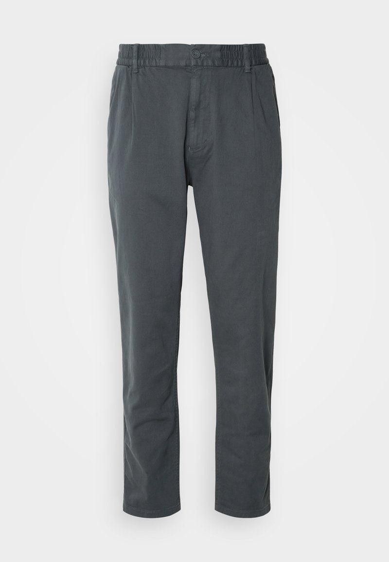 Graue Baumwollhose mit lockerer Passform, ausgestattet mit einem elastischen Bund, Knopfverschluss und seitlichen Taschen, auf einem weißen Hintergrund präsentiert.