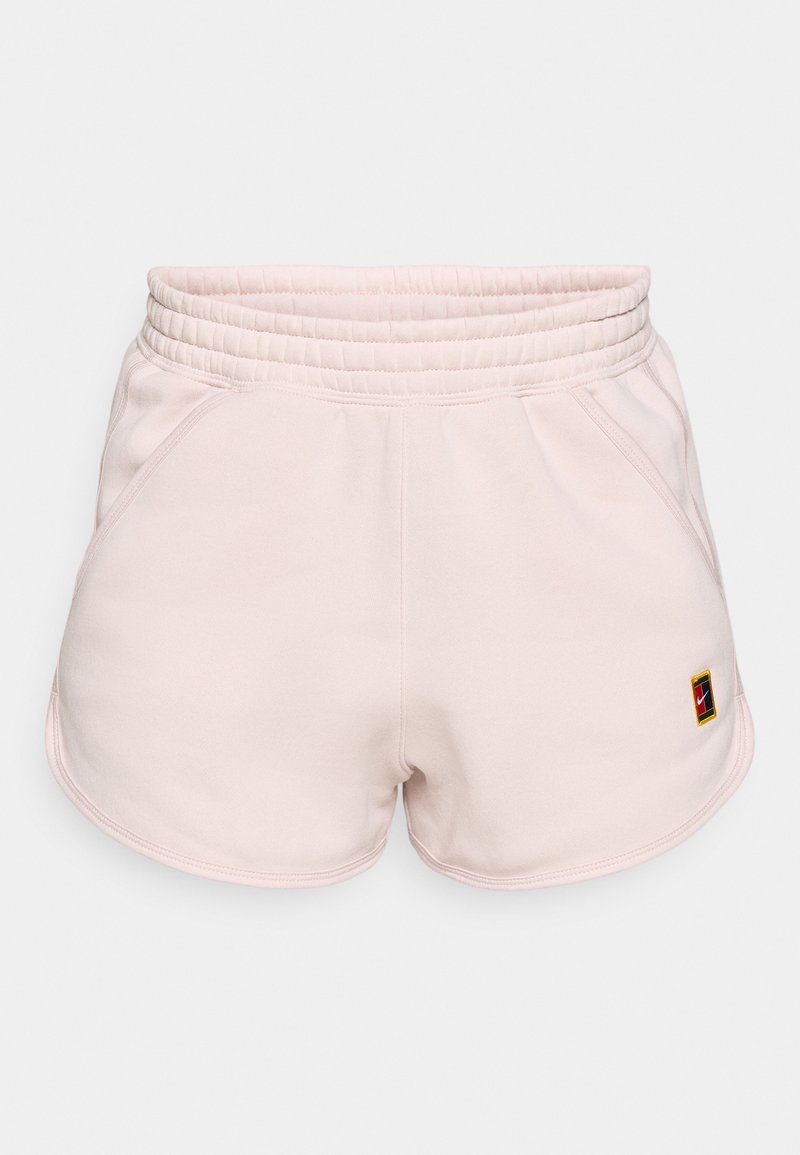 Helle pinke Sportshorts mit einem breiten elastischen Bund, seitlichen Taschen und einem kleinen Logo-Aufnäher auf der unteren linken Seite. Sanfte Stofftextur.