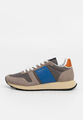 Graue und beige Sneaker mit blauem Seitenpanel, weißen Schnürsenkeln, orangefarbener Fersenschlaufe und beigem Sohlen mit schwarzem Profil.