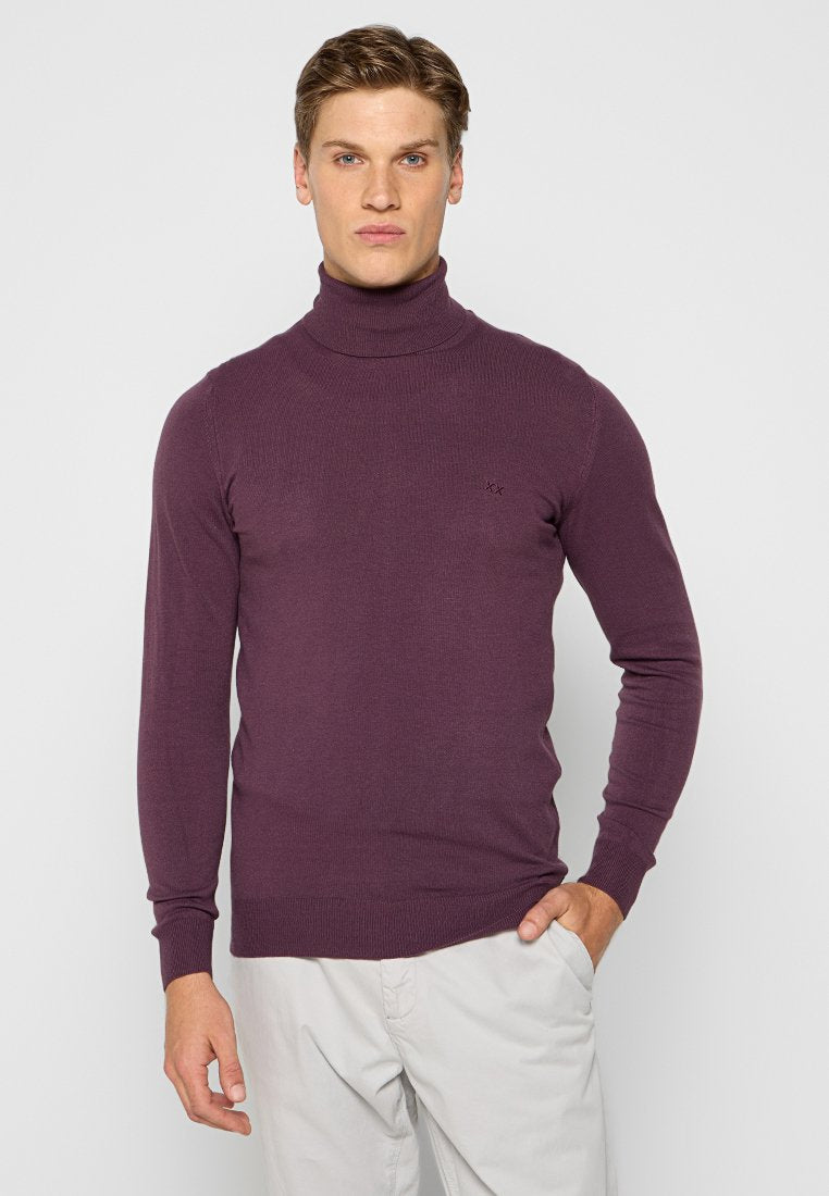 Lila Rollkragenpullover mit geripptem Muster, langen Ärmeln und einem Logodetail auf der Brust. Der Stoff scheint weich und figurbetont zu sein.