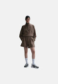 Brauner Fleece-Pullover mit halbem Reißverschluss-Kragen, kombiniert mit passenden Shorts. Das Model trägt weiße Socken und graue Sportschuhe. Einfaches Design, lässige Passform.