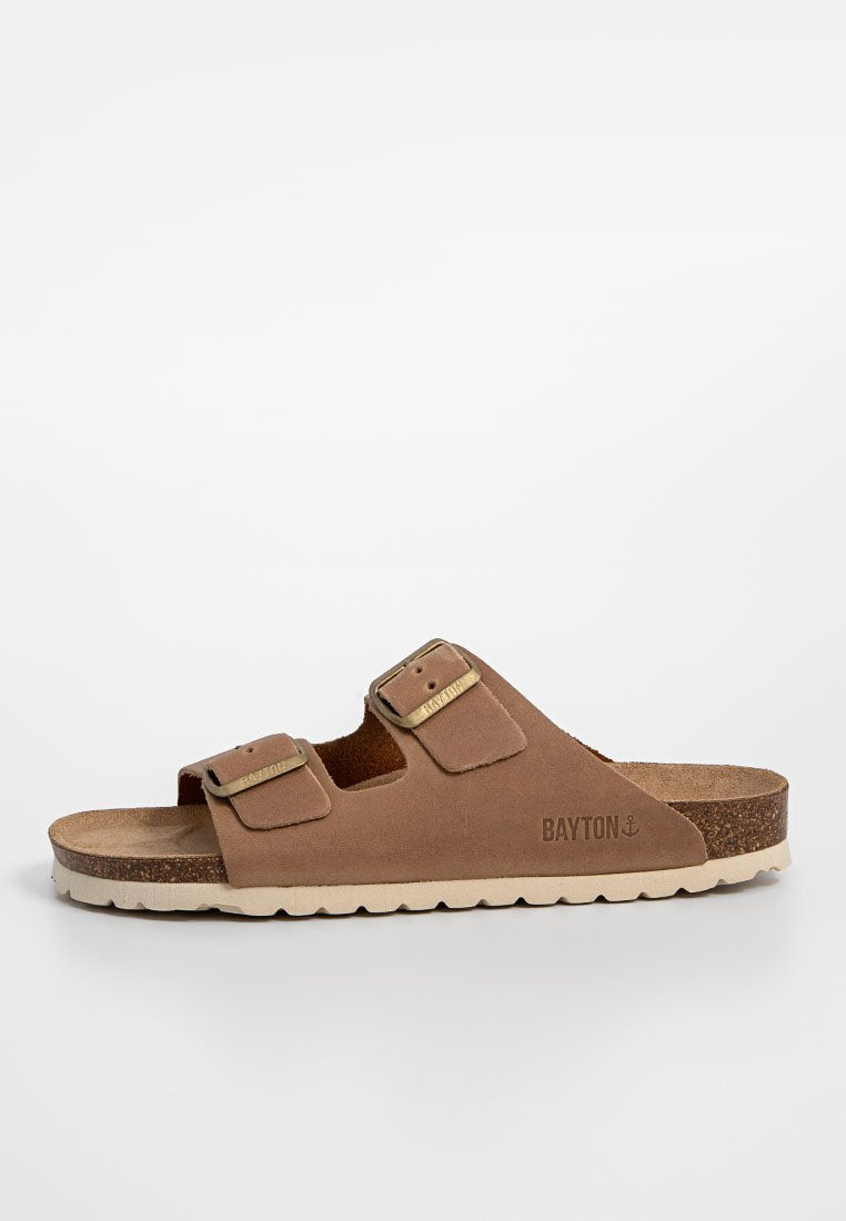 Braune Wildledersandalen mit zwei verstellbaren Riemen, goldfarbenen Schnallen und einer strukturierten Korksohle. Die weiße Sohle hat ein welliges Muster.
