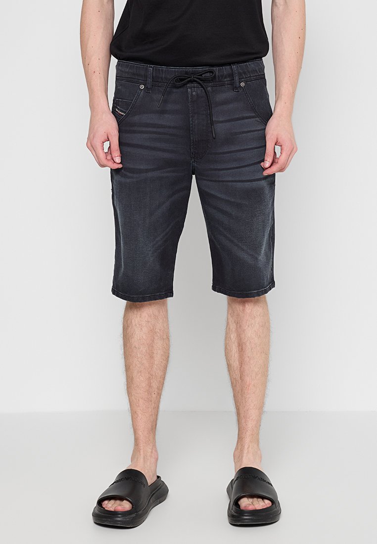 Männer Denim-Shorts in Dunkelgrau mit einem Kordelzugbund, zwei Vorderseiten-Taschen und einem geraden Schnitt. Getragen mit schwarzen Riemchensandalen.