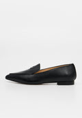 Schwarzer Leder-Slipper mit spitz zulaufender Zehenpartie, flachem Absatz und strukturierter Oberfläche, Seitenansicht vor einfarbig hellem Hintergrund.