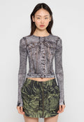 Langärmliges, geschnittenes Oberteil mit Denim-Print, knöpfbare Vorderseite und Brusttaschen; kombiniert mit einem grün-beigen Camouflage-Rock mit Reißverschluss und großen Taschen.