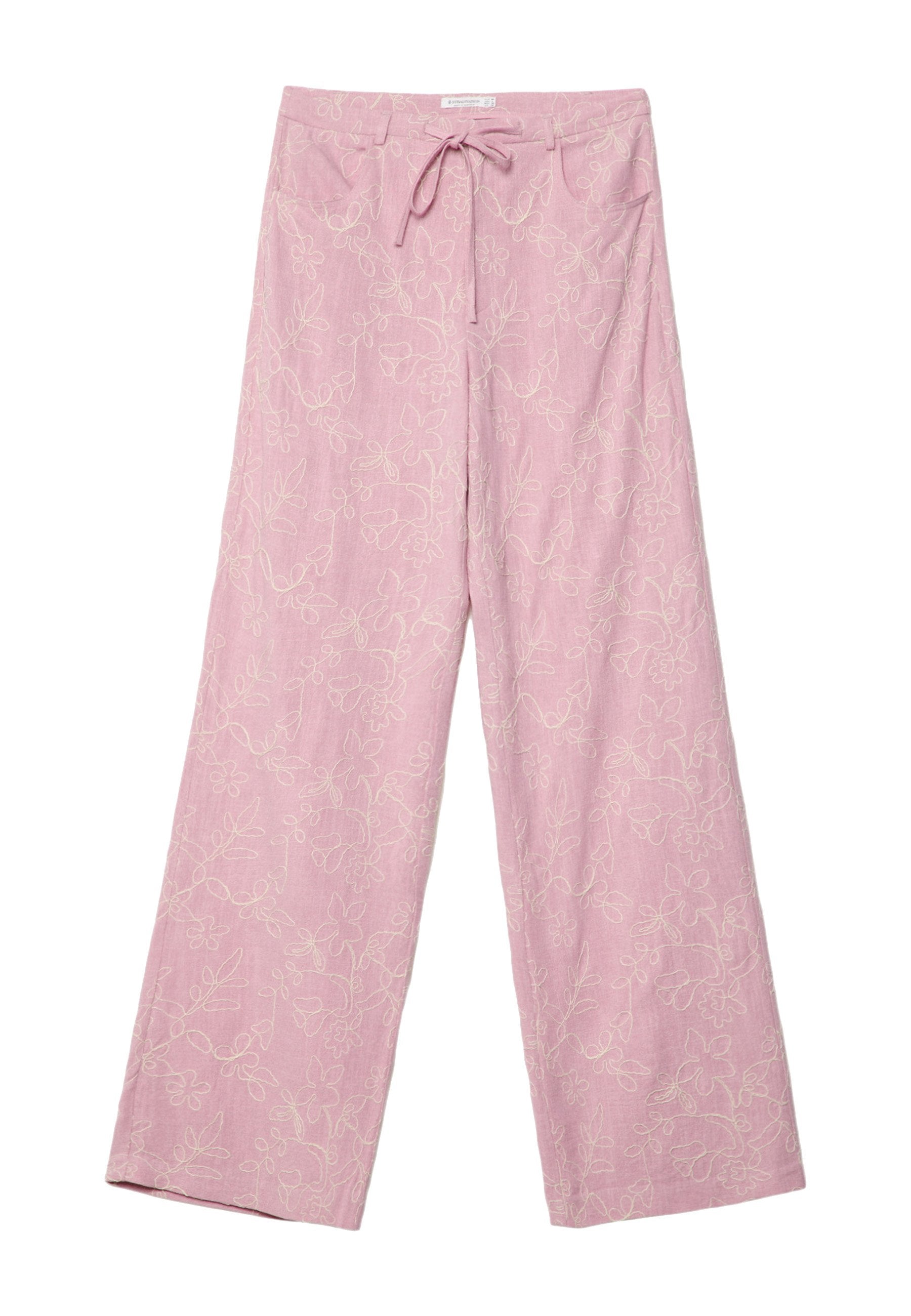 Helle rosa weit geschnittene Hose mit floralem Muster in weißer Stickerei, Bindegürtel und zwei Fronttaschen aus einem weichen, strukturierten Stoff.
