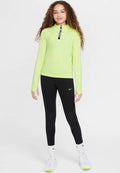 Langärmliges, leuchtend limettengrünes Sportoberteil mit einem halben Reißverschluss, kombiniert mit schwarzen Leggings mit strukturiertem Muster und weißen Sneakers.