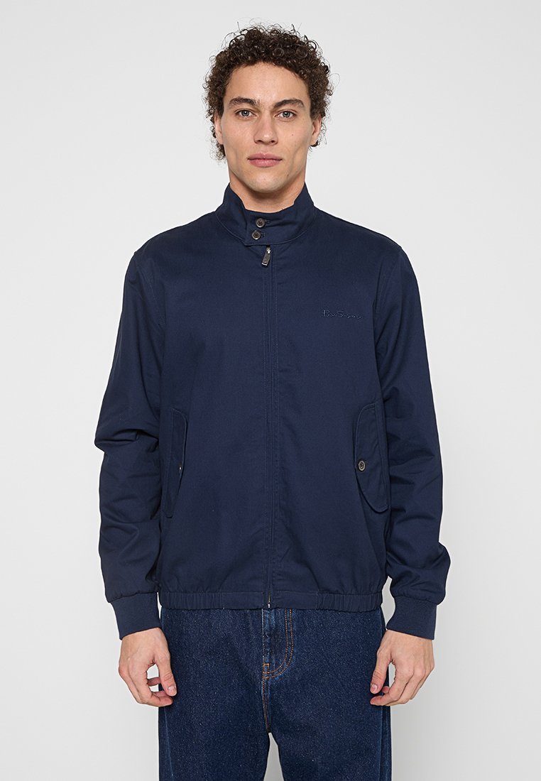 Marineblau leichte Jacke mit hohem Kragen, Frontreißverschluss, zwei Seitentaschen und elastischen Bündchen sowie einer glatten Stoffoberfläche.