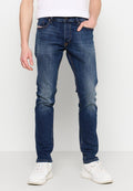 Dunkelblaue Denim-Jeans mit schmalem Schnitt, verblassten Stellen, kontrastierenden Nähten und Fünf-Taschen-Design, kombiniert mit weißen Sneakers.
