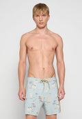 Hellblaue Badehose aus einem Stoff mit tropischem Druck, der Palmen, Boote und Sonnenelemente zeigt. Enthält einen gelben Kordelzug.