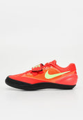 Niedriger roter Nike Sportschuh mit neongrünem Swoosh, schwarzer Sohle, Schnürsenkeln und einem Klettverschluss über dem Mittelfuß vor weißem Hintergrund.