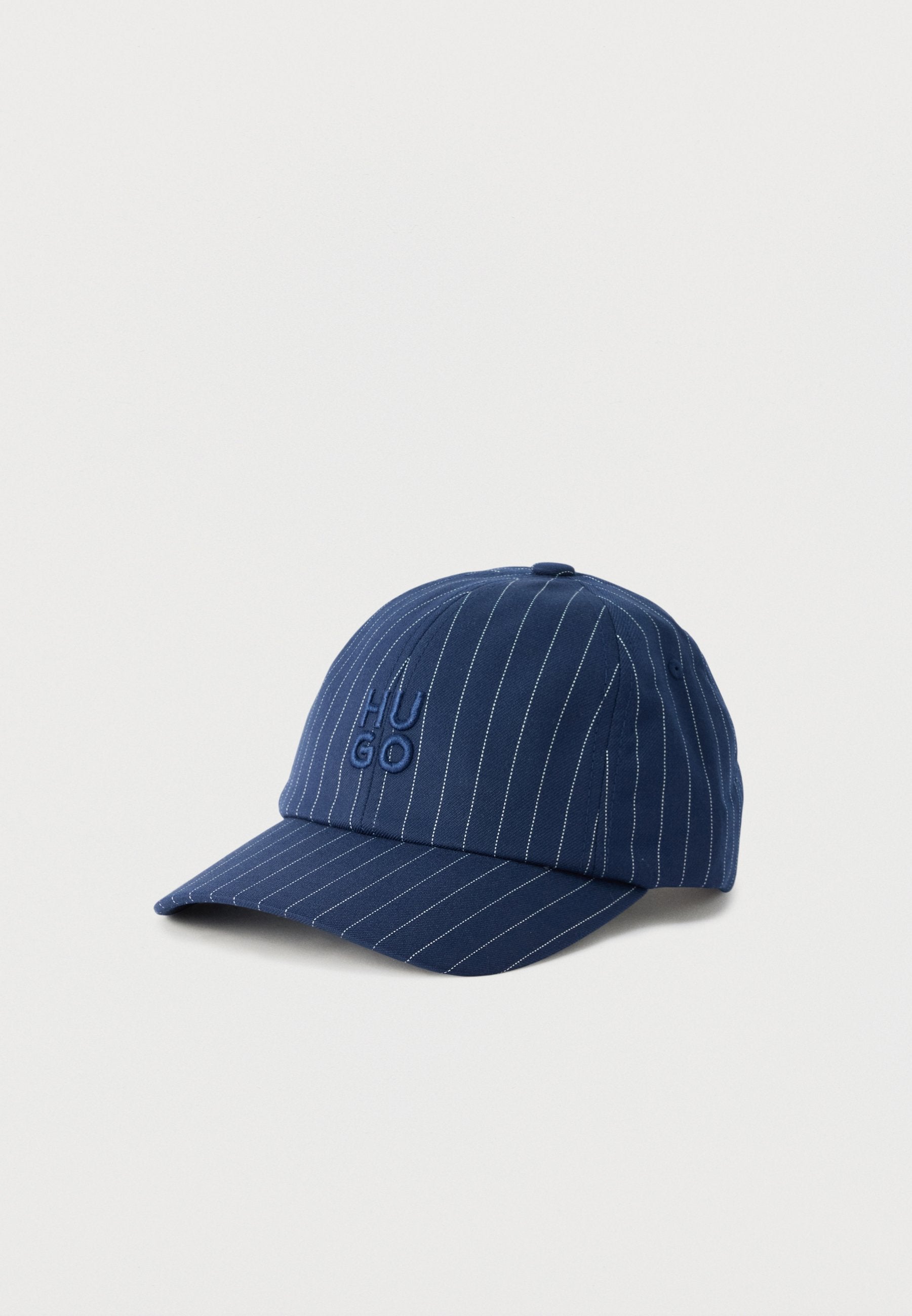 Marineblaue Baseballkappe mit weißen Nadelstreifen und geprägt "HUGO"-Logo auf der Vorderseite, präsentiert auf einem schlichten weißen Hintergrund.