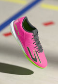 Rosa Sportschuh mit strukturiertem Obermaterial, grauen Schnürsenkeln und grünen Akzenten. Verfügt über eine weiße Sohle und ein erhabenes Logo an der Seite.