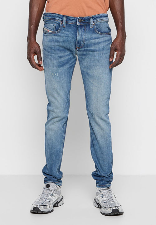 Helle blaue Denim-Jeans mit schlankem Schnitt, fünf Taschen und dezenten Verwaschungen. Mit orangem Nähen und Knopfverschluss.