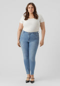 Hellblaue Skinny-Jeans mit hoher Taille, subtilen Used-Effekten und einer glatten Denim-Oberfläche, kombiniert mit einem figurbetonten weißen Oberteil.