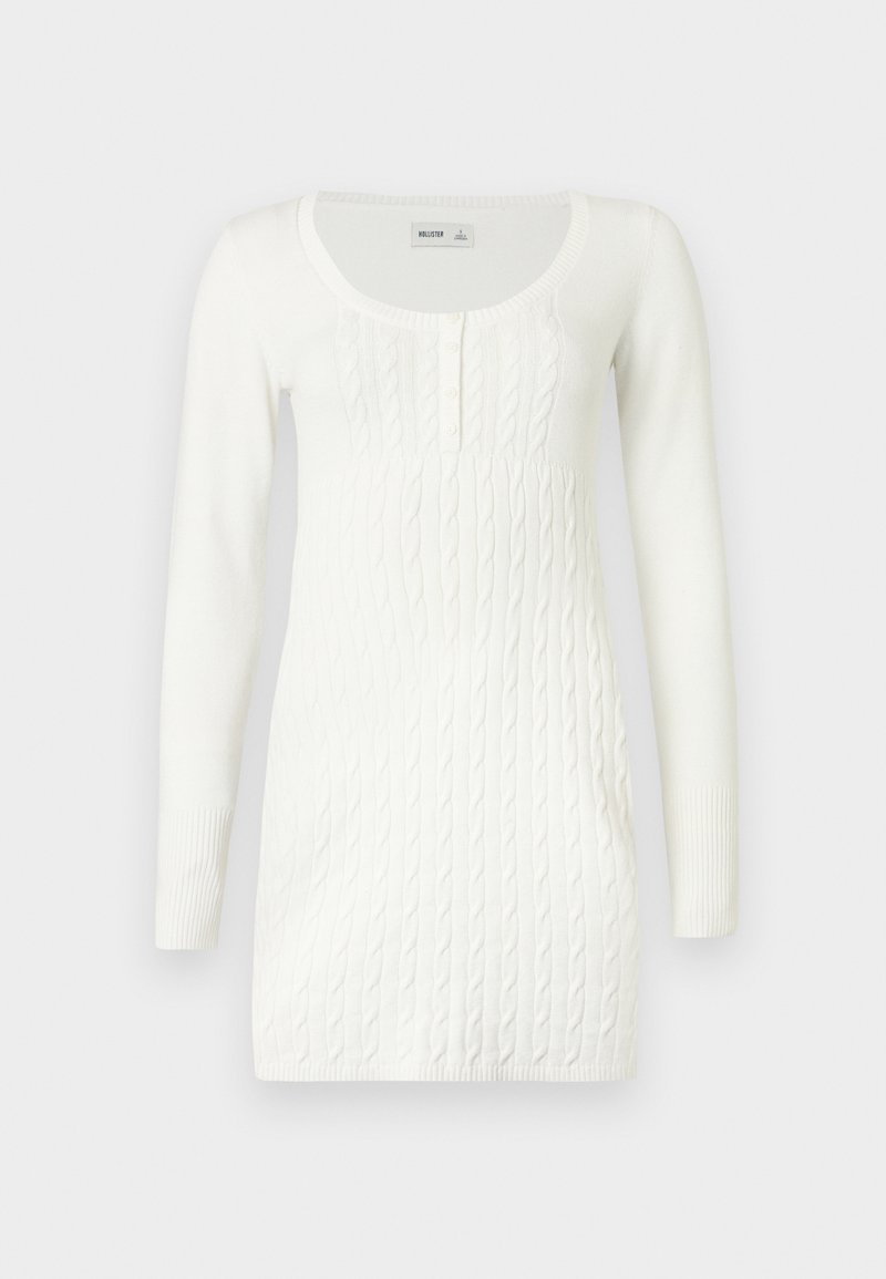 Weißes langärmeliges Strickkleid mit Zopfmuster, Rundhalsausschnitt und Knopfleiste auf unifarbenem Hintergrund.
