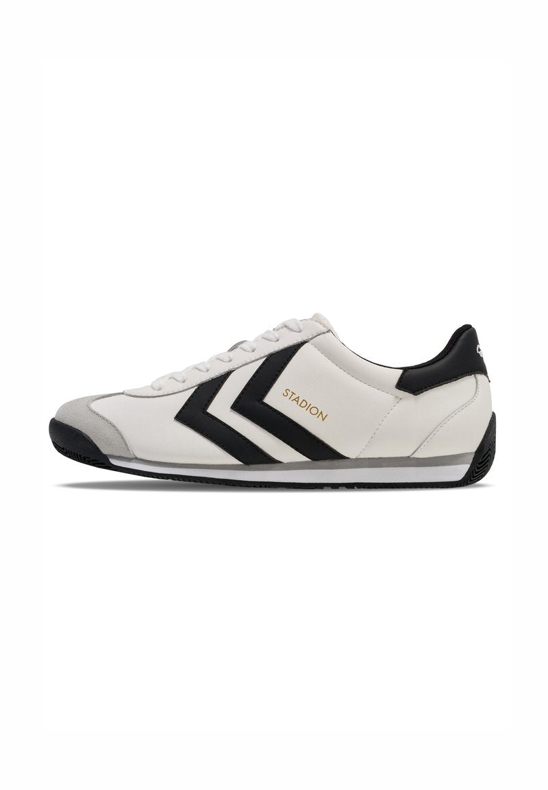 Weißer Sportschuh mit schwarzen Akzenten, zwei auffälligen schwarzen Chevrons an der Seite, grauem Zehenbereich und strukturiertem Außensohle. Goldenes Markennamensdetail.