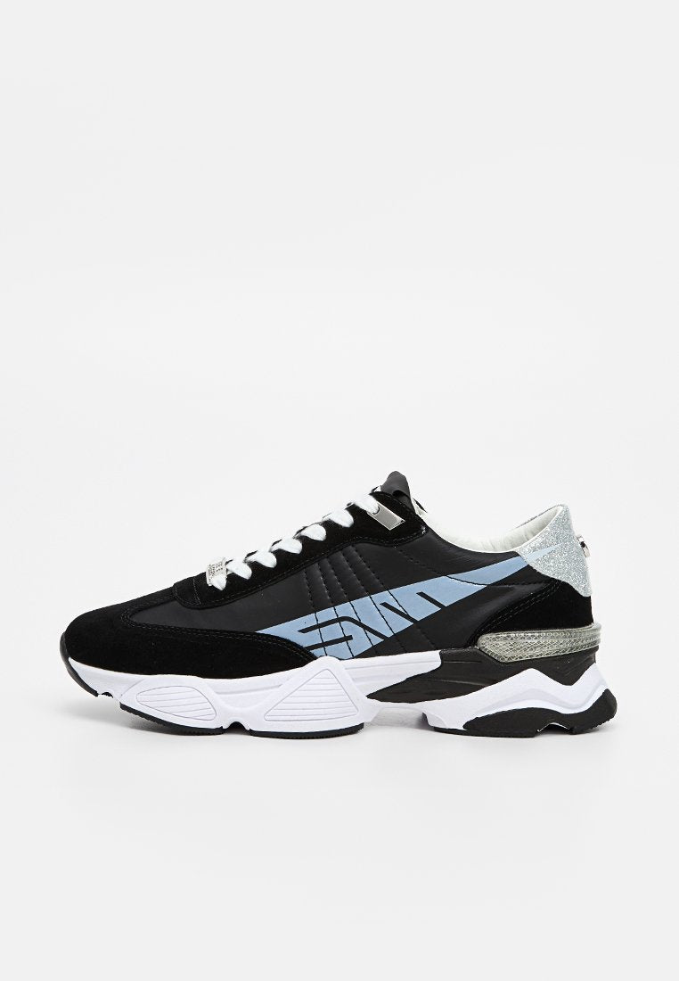 Schwarz-weißer Sneaker mit hellblauem Streifen, weißen Schnürsenkeln, silberner Glitzer-Ferseneinsatz und dicker Sohle auf einem weißen Hintergrund.