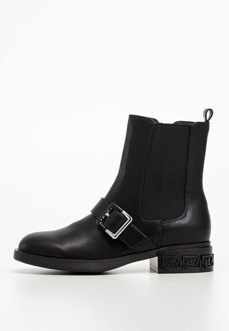 Schwarze Knöchelstiefel aus glattem Leder mit elastischen Seitenpanels, einem metallischen Schnallenriemen und einem dekorativen gemusterten Blockabsatz.