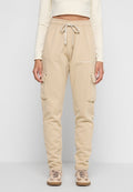 Beige Cargo-Sweatpants mit weichem Material, einer Zugbandtaille und Seitentaschen. Mit weißem Branding am Oberschenkel.