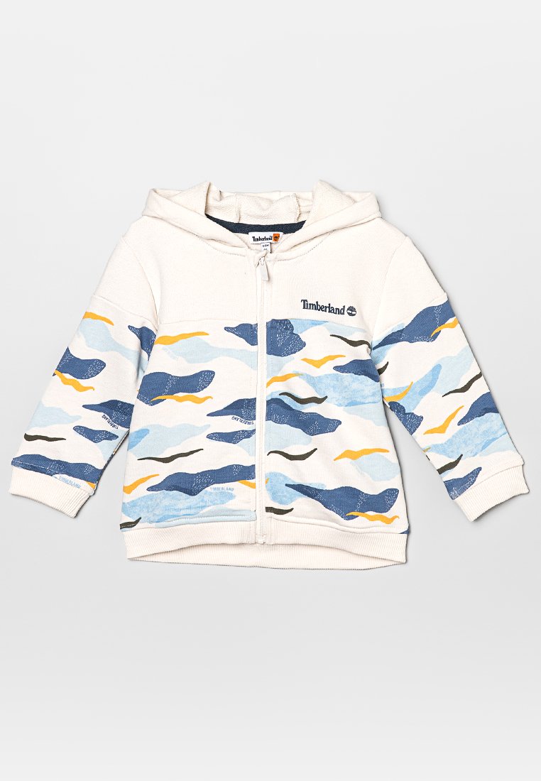Zip-Hoodie aus weichem Stoff mit einer cremefarbenen Basis und Wellenmustern in Blau, Gelb und Schwarz. Mit Kapuze und gerippten Bündchen.