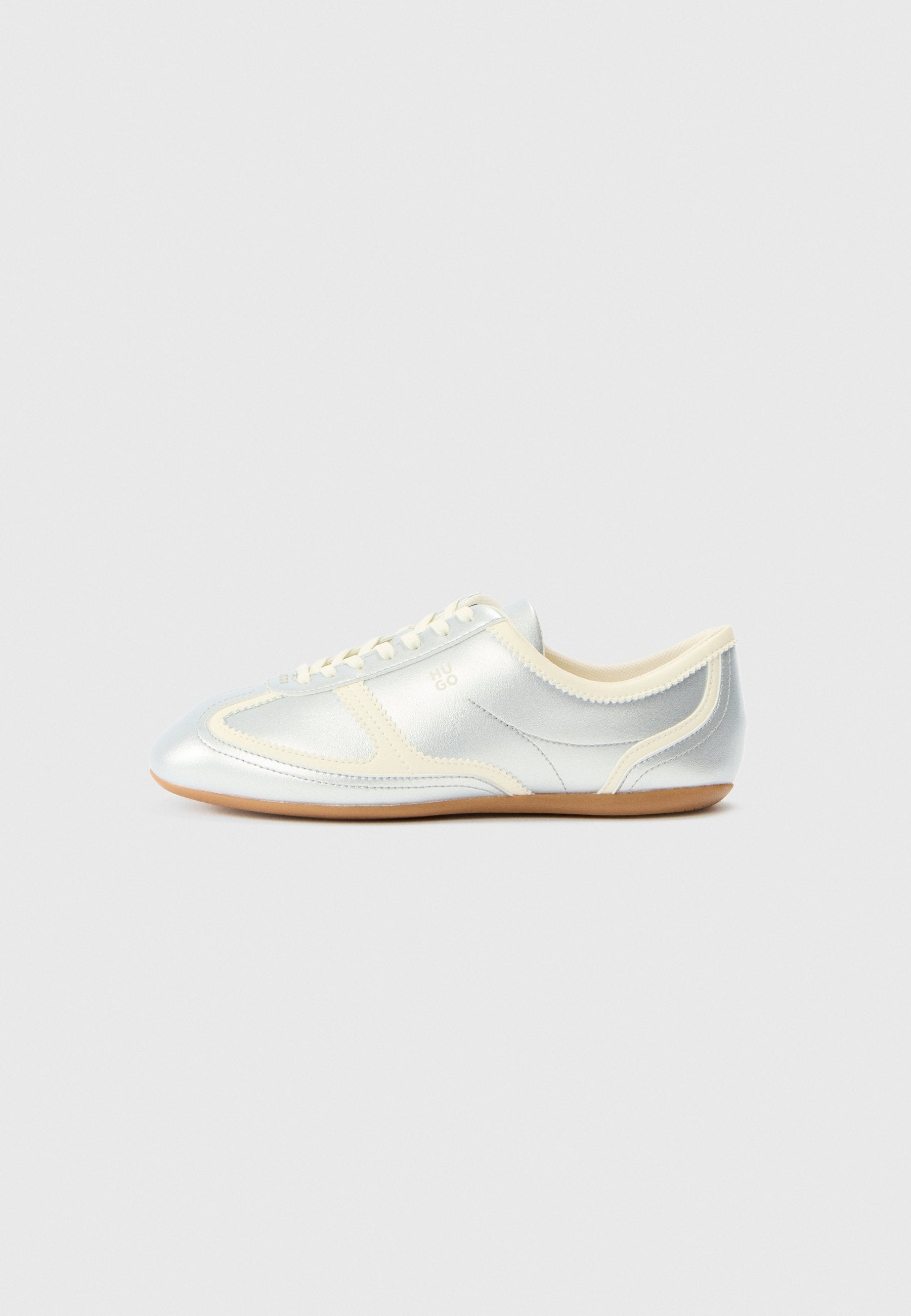 Silberne, synthetische Sneaker mit cremefarbenen Akzenten, flachem Profil, rundem Zehenbereich und flacher Gummisohle; verfügt über klassische Nahtdetails und Schnürverschluss.