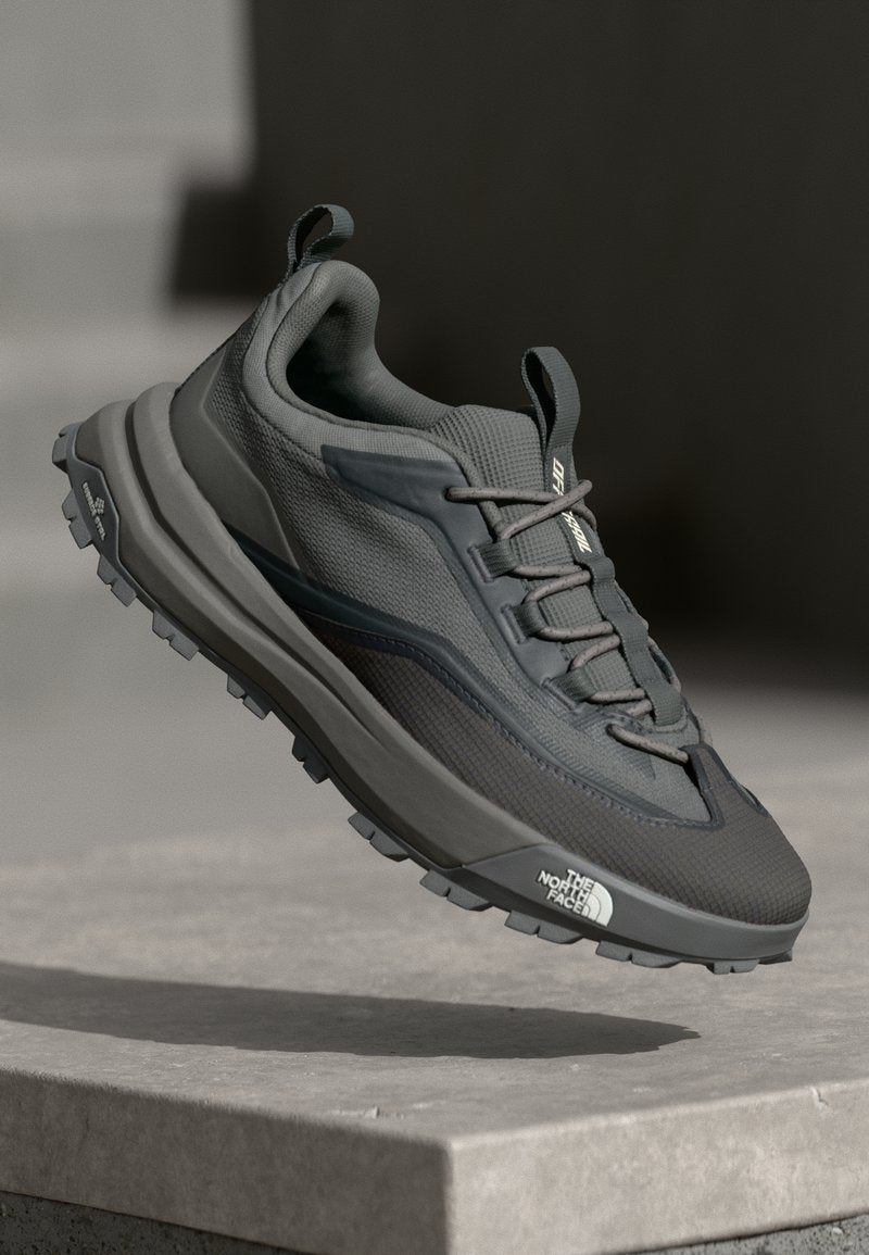 Graue Trailrunning-Schuhe mit einem strukturierten Obermaterial aus Stoff, verstärkter Zehenpartie und flexibler Gummisohle mit ausgeprägten Stollen für Traktion.