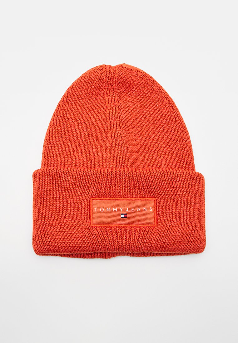 Helles oranges gestricktes Beanie mit umgeschlagenem Bund, der eine rechteckige "Tommy Jeans"-Logo-Patch und ein kleines Flaggenemblem auf der Vorderseite zeigt.